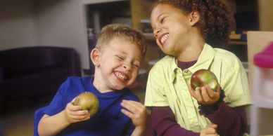 Two students smiling and eating an apple